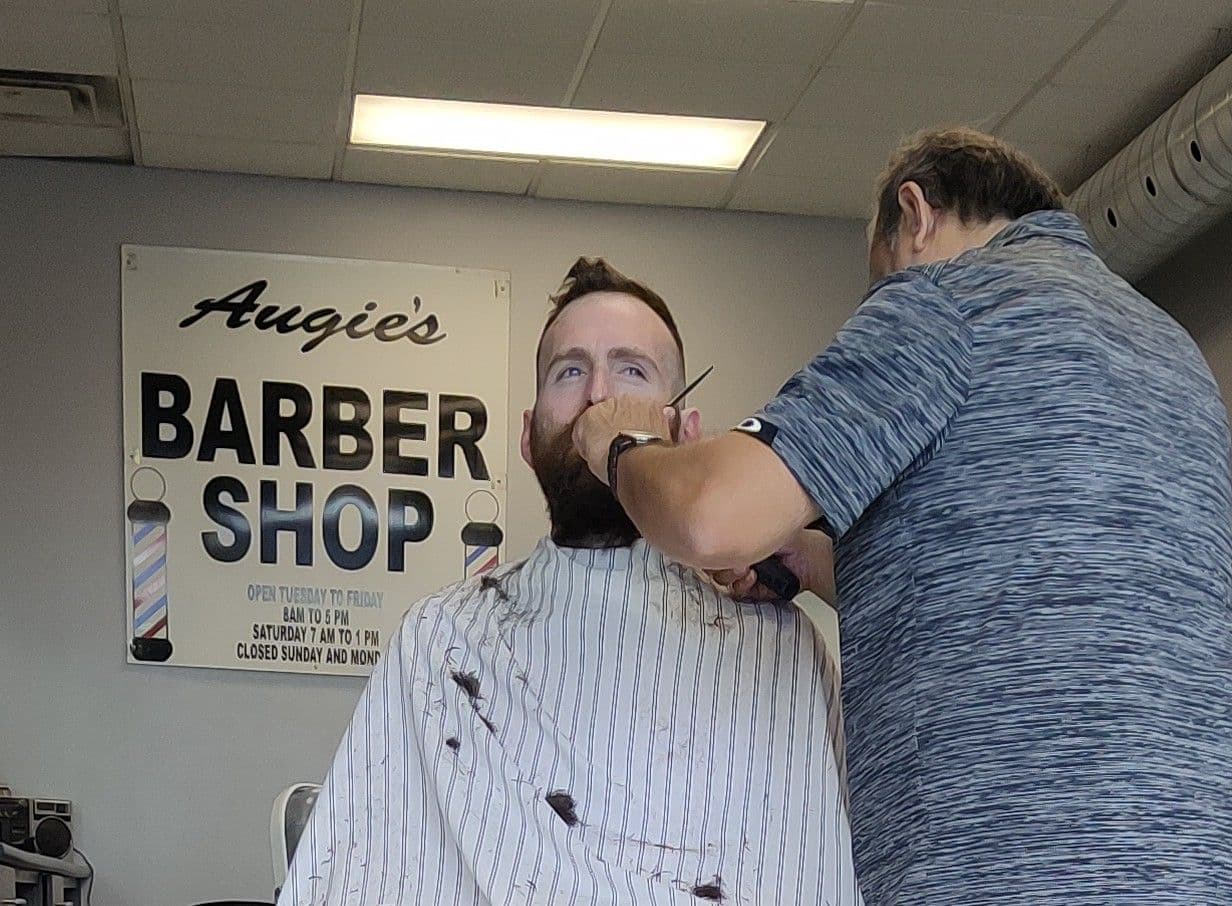 Augie's Barber Shop team reviewing guest feedback at the front desk between appointments