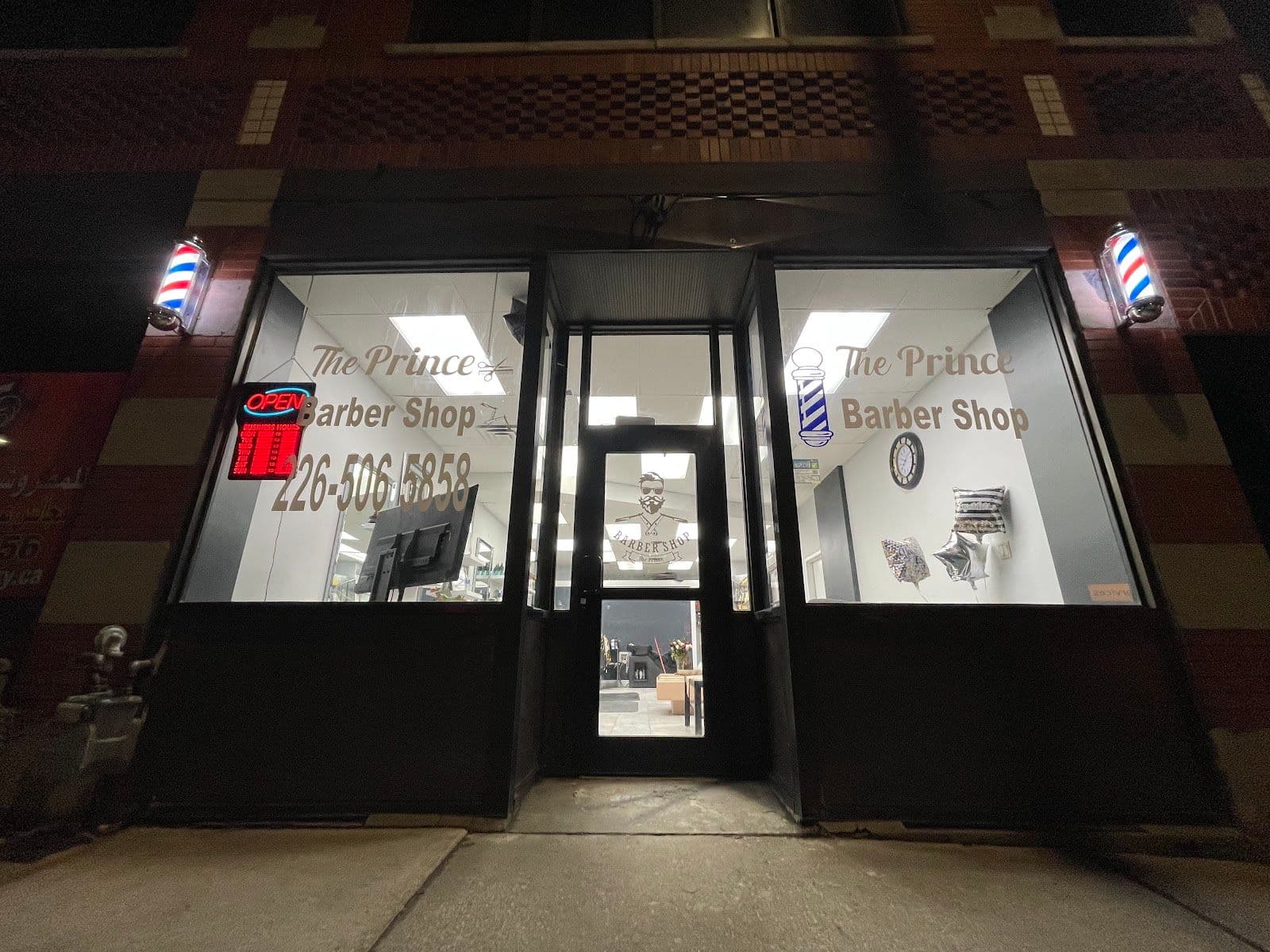 The Prince Barbershop owner reviewing guest feedback and Google ratings on a tablet at the front of the shop