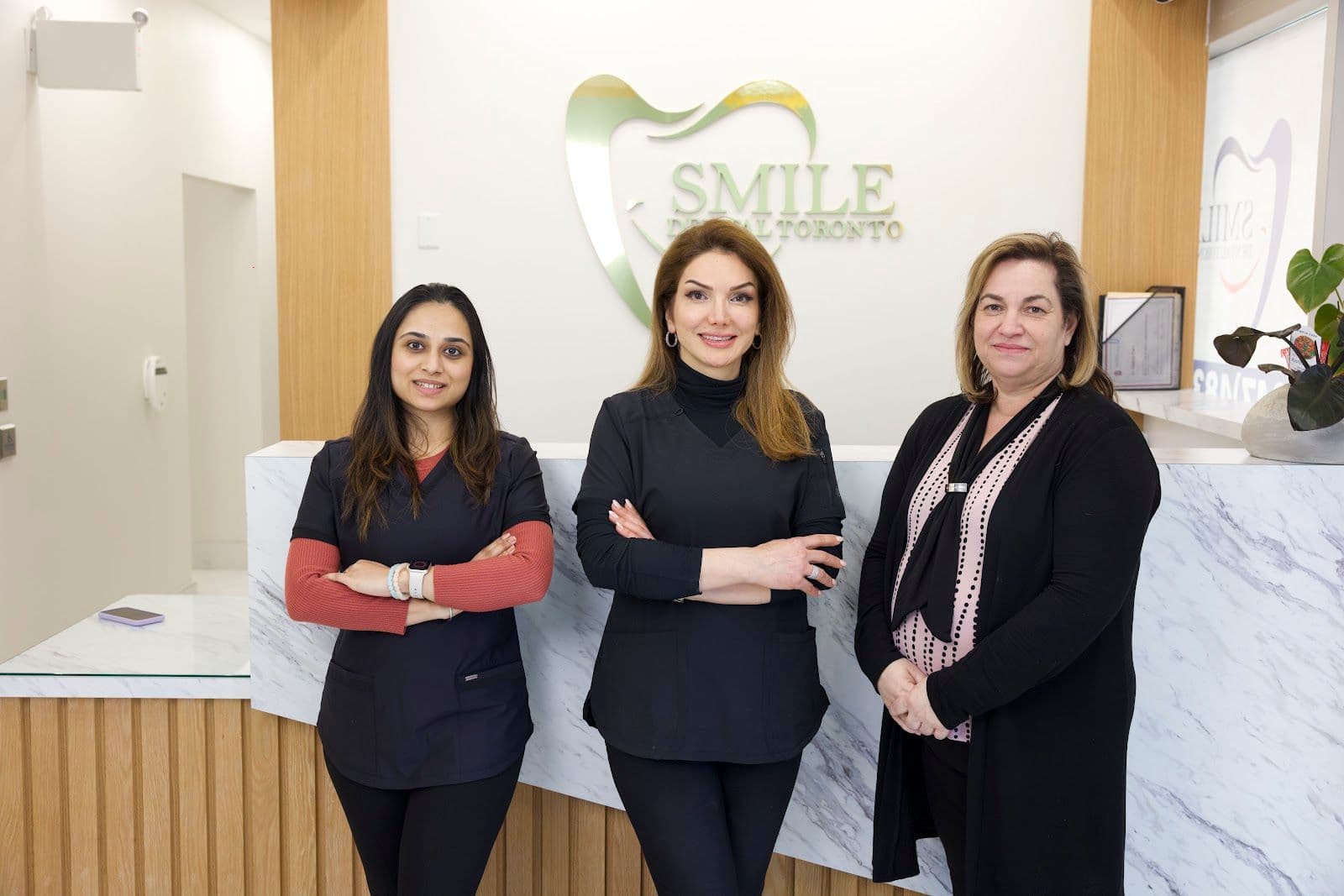 Dr. Rashin Elahi and her front desk team at Smile Dental Centre Toronto reviewing patient feedback together at the clinic