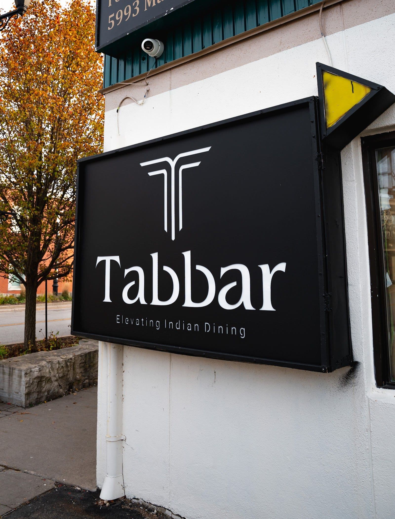 Restaurant team at Tabbar Social Kitchen & Bar reviewing guest feedback together on a tablet near the dining area