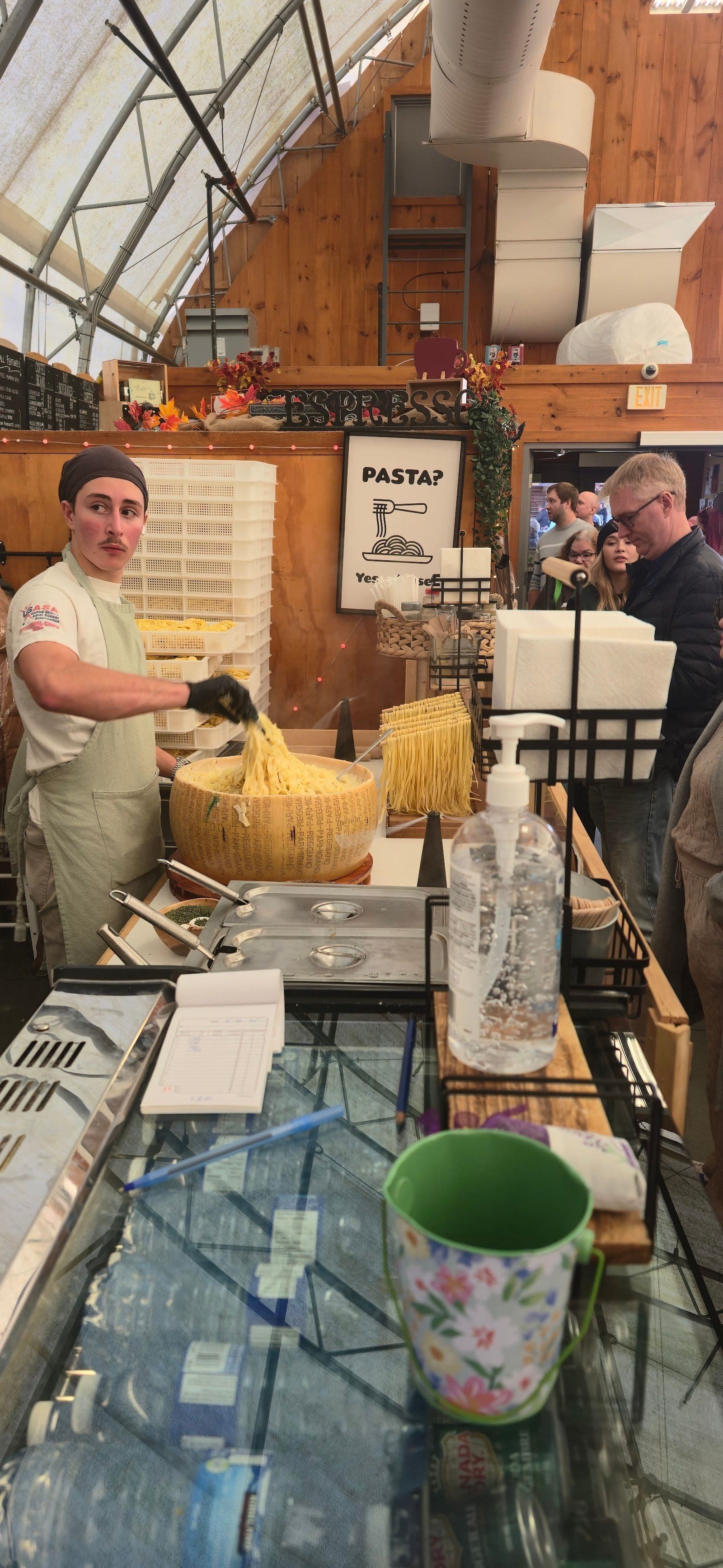 Restaurant team at Cheesy Busy Wheel Inc. reviewing guest feedback on a tablet at their St Jacobs market stall.